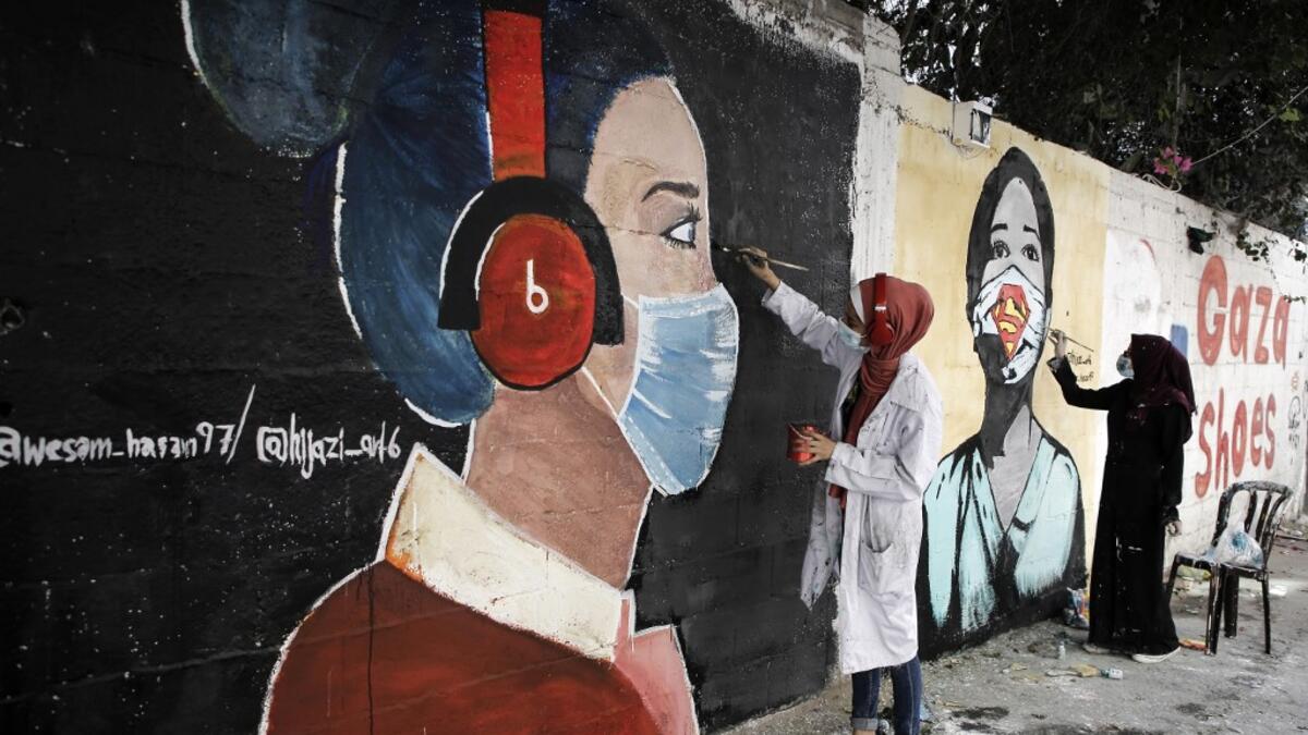 Palestinian students paint murals of mask-clad young girls in Gaza City on October 22, 2020, amid the novel coronavirus pandemic crises. Mohammed ABED / AFP