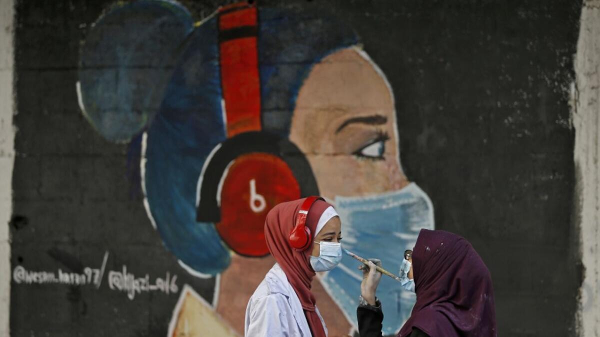 Palestinian students interact as they paint murals of a mask-clad girls in Gaza City on October 22, 2020, amid the novel coronavirus pandemic crises. Mohammed ABED / AFP