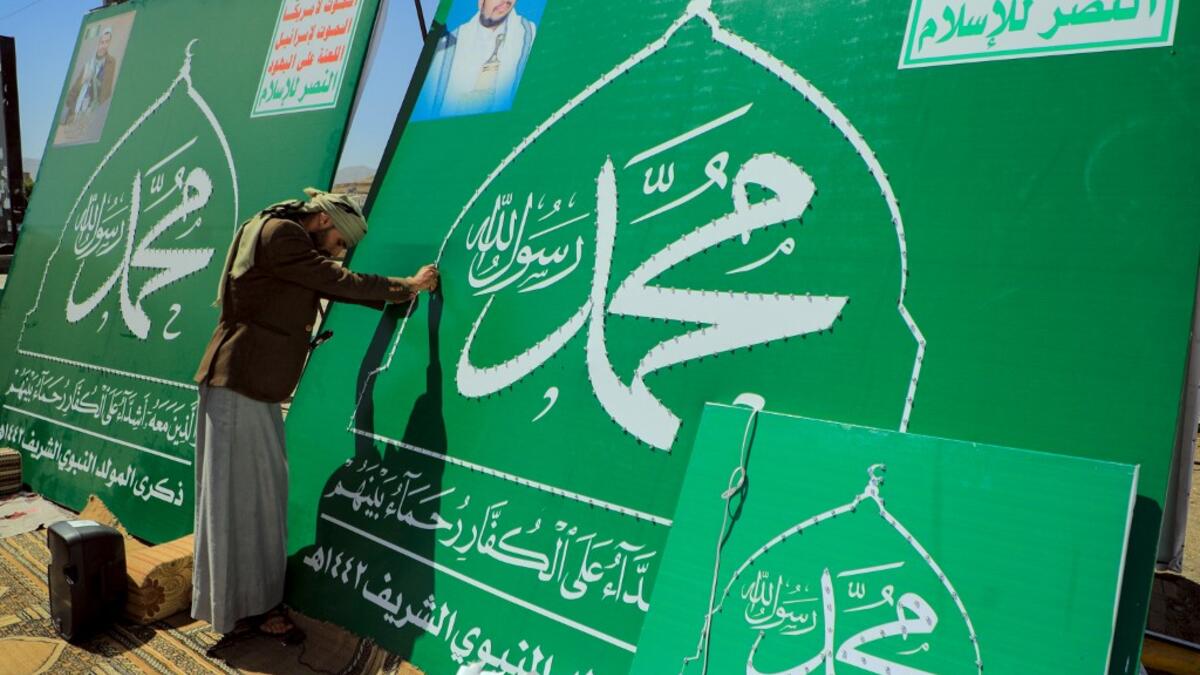 A Yemeni man adjusts the lights on a sign bearing the name of Islam's Prophet Mohammad and the portrait of Shiite Huthi rebel leader Abdul-Malik al-Huthi in the capital Sanaa on October 24, 2020, in response to comments by French President Emmanuel Macron defending cartoons of the Prophet Mohammed. Mohammed HUWAIS / AFP