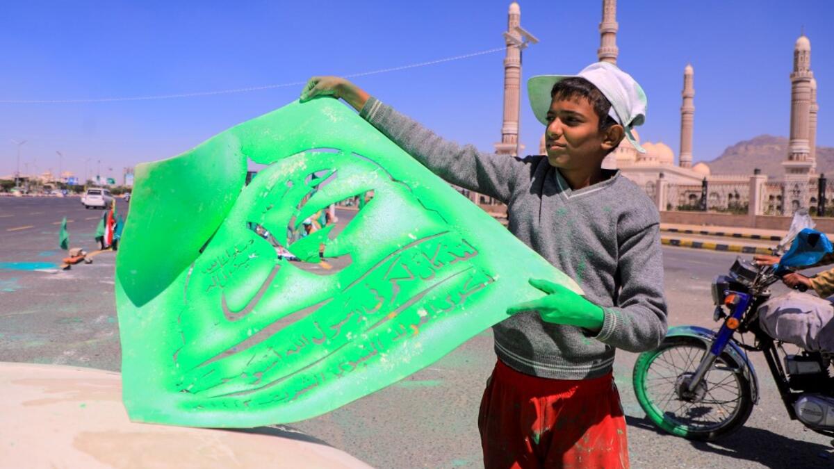 A Yemeni man adjusts a stencil bearing the name of Islam's Prophet Mohammad before spray painting it on a truck in front of Al-Saleh mosque in the capital Sanaa on October 24, 2020, in response to comments by French President Emmanuel Macron defending cartoons of the Prophet Mohammed. MOHAMMED HUWAIS / AFP