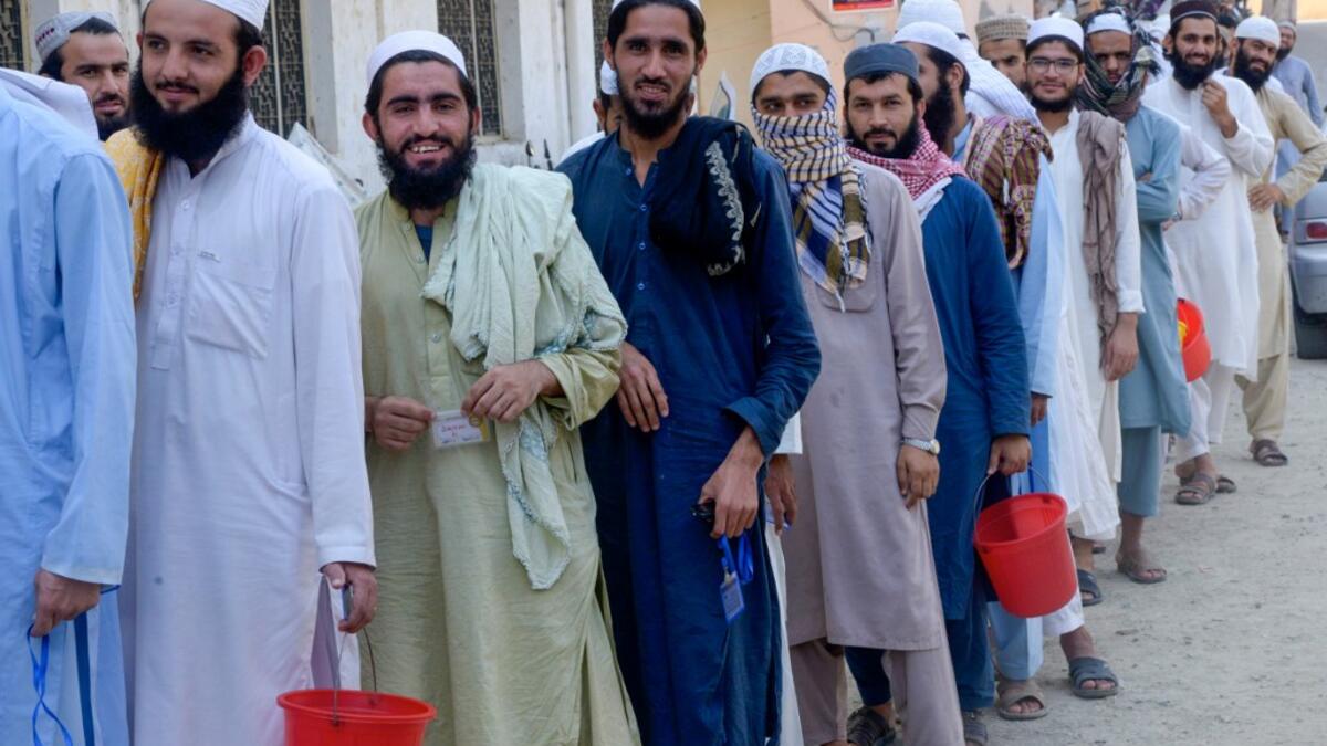 In this picture taken on October 19, 2020 Islamic seminary students wait to collect food at the Darul Uloom Haqqania seminary in Akora Khattak. The Darul Uloom Haqqania seminary has churned out a who's who of Taliban top brass -- including many now on the hardline group's negotiating team holding talks with the Kabul government to end a 20-year war. Abdul MAJEED / AFP