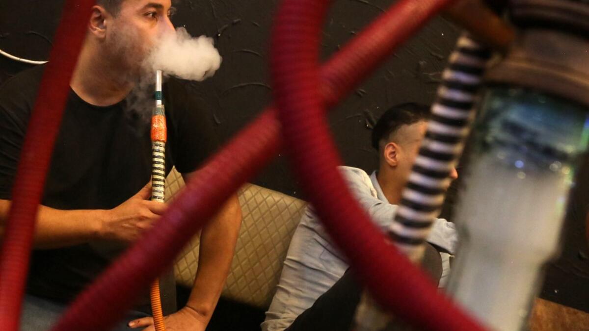 Iraqi men smoke narguileh (water pipe) at a coffee shop in Iraq's central holy city of Karbala on October 21, 2020. The narguileh business of strictly gender-separated cafes has carried on, despite the heavy health risks associated with smoking and a full-blown pandemic that has brought an average of 4,000 new coronavirus cases a day to Iraq. Mohammed SAWAF / AFP
