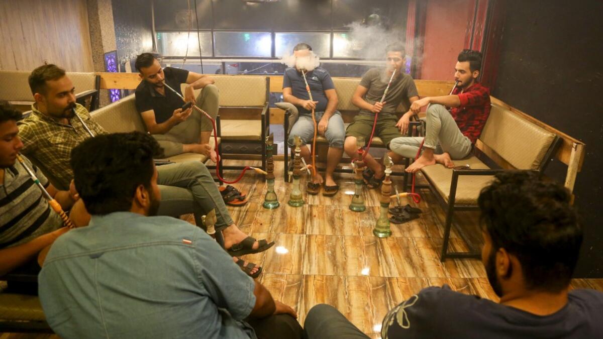 Iraqi men smoke narguileh (water pipe)at a coffee shop in Iraq's central holy city of Karbala on October 21, 2020. The business of strictly gender-separated cafes has carried on, despite the heavy health risks associated with smoking and a full-blown pandemic that has brought an average of 4,000 new coronavirus cases a day to Iraq. Mohammed SAWAF / AFP