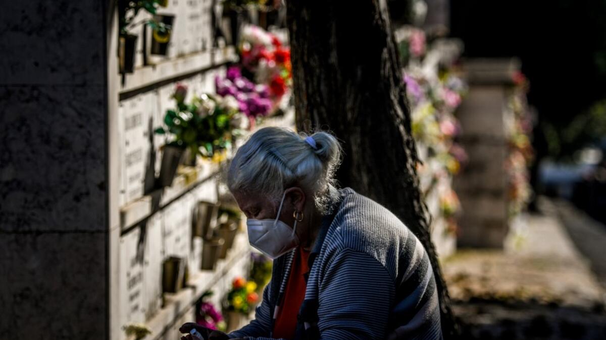 A woman wearing a face mask disinfects her hands at the Alto de Sao Joao cemetery in Lisbon on October 30, 2020 on the eve of All Saints' Day amid the coronavirus pandemic. PATRICIA DE MELO MOREIRA / AFP