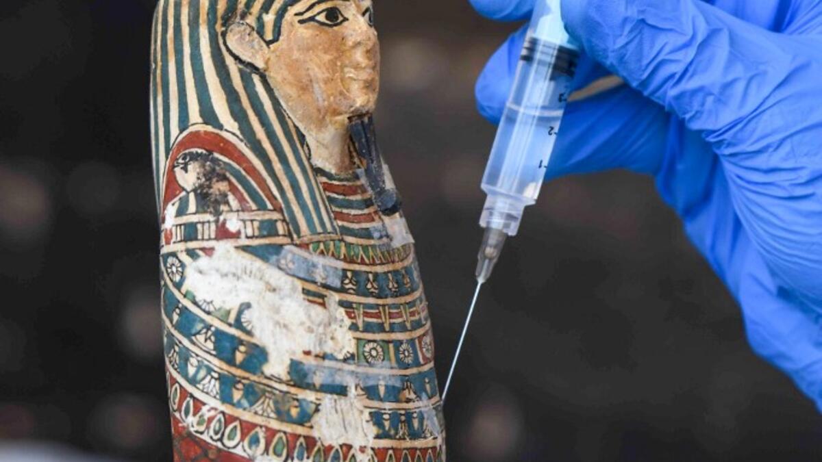 An archaeologist cleans a statue during the unveiling of an ancient treasure trove of more than a 100 intact sarcophagi, at the Saqqara necropolis 30 kms south of the Egyptian capital Cairo, on November 14, 2020. Egypt announced the discovery of an ancient treasure trove of more than a 100 intact sarcophagi, the largest such find this year. The sealed wooden coffins, unveiled on site amid fanfare, belonged to top officials of the Late Period and the Ptolemaic period of ancient Egypt. They were found in thre