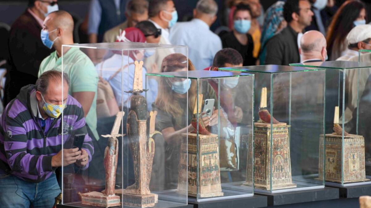 A picture shows statues and funerary masks on display during the unveiling of an ancient treasure trove of more than a 100 intact sarcophagi, at the Saqqara necropolis 30 kms south of the Egyptian capital Cairo, on November 14, 2020. Egypt announced the discovery of an ancient treasure trove of more than a 100 intact sarcophagi, the largest such find this year. The sealed wooden coffins, unveiled on site amid fanfare, belonged to top officials of the Late Period and the Ptolemaic period of ancient Egypt. Th