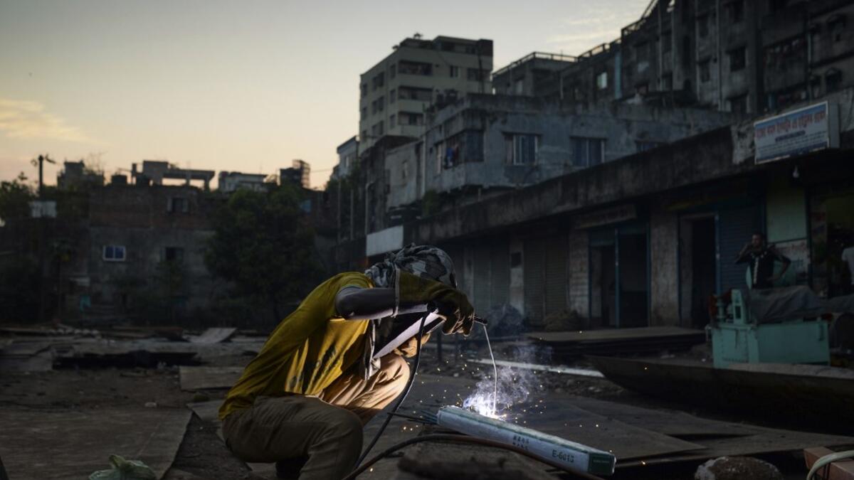 In this picture taken on November 12, 2020 a dockyard worker welds a ship's part on the banks of the Buriganga River in Char Kaliganj on the outskirts of Dhaka. Rivers are the lifeblood of the delta nation of 168 million people where much of the low-lying land is accessed via boat, with Bangladesh's strong economic growth of recent years fuelling more investments in new and bigger ships. Munir UZ ZAMAN / AFP