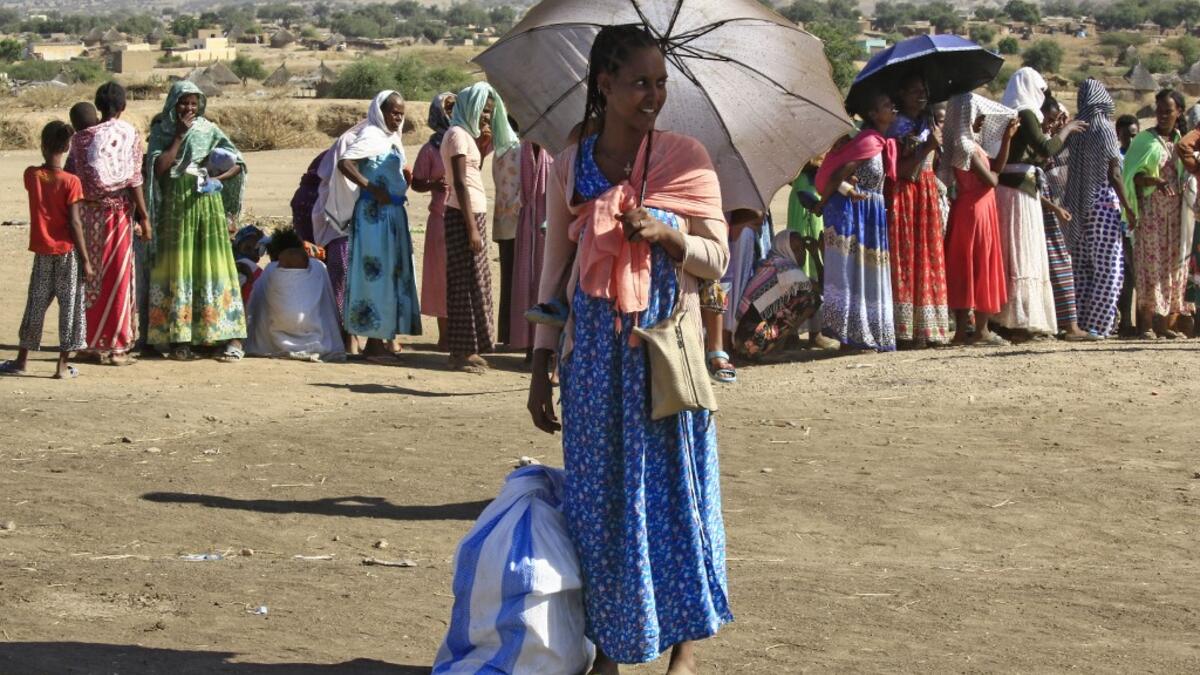 Ethiopian refugees who fled the fighting in the Tigray region gather upon arrival to a reception center in the Hamdayit area of Sudan's eastern Kassala state, on November 22, 2020. The placard reads "stop for inspection". ASHRAF SHAZLY / AFP