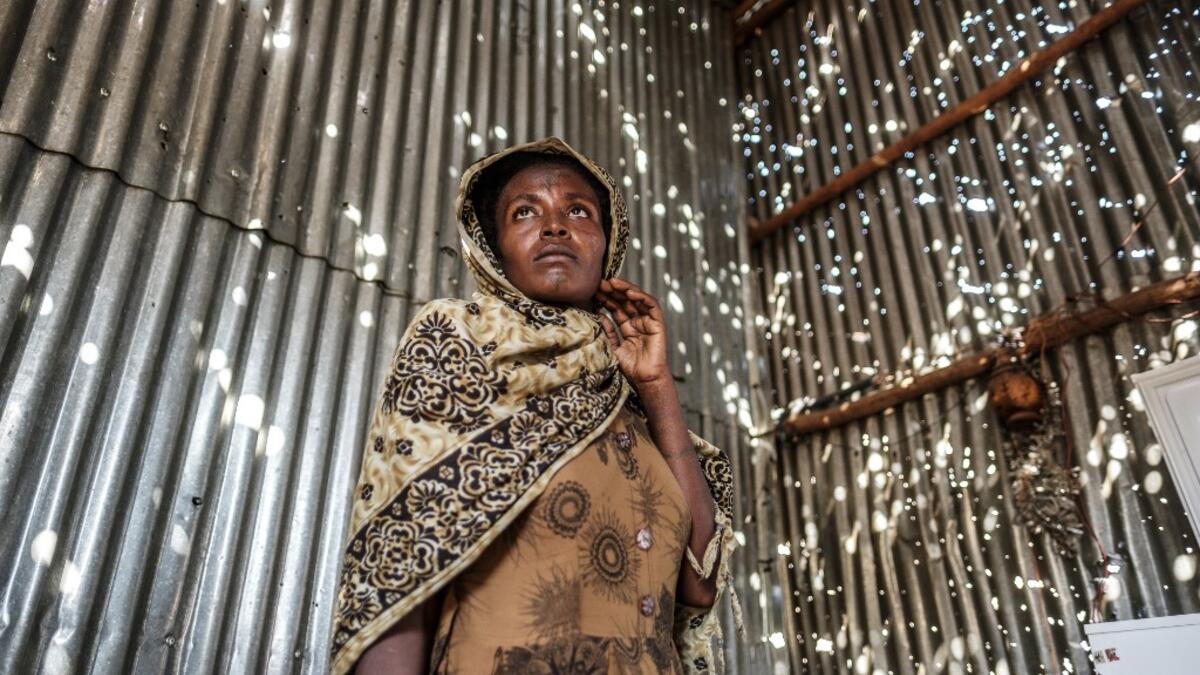 A woman stands in a metal sheet room that was damaged by shelling, in Humera, Ethiopia, on November 22, 2020. In that residential compound, two women and an elderly man were killed by shelling and gunfire, while two other women remain on makeshift stretchers as they recover from their wounds. EDUARDO SOTERAS / AFP