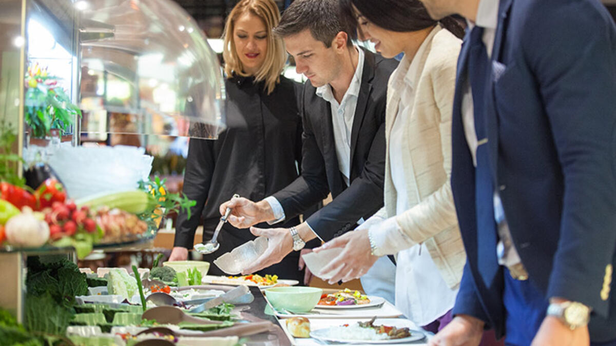 المقصف ذو الخدمة الذاتيّة: سترى نادلًا يرتدي قناع الوجه والقفازات ويقف خلف طاولة المقصف في انتظار أن يقدم لك البيض المخفوق والفاكهة المقطعة.