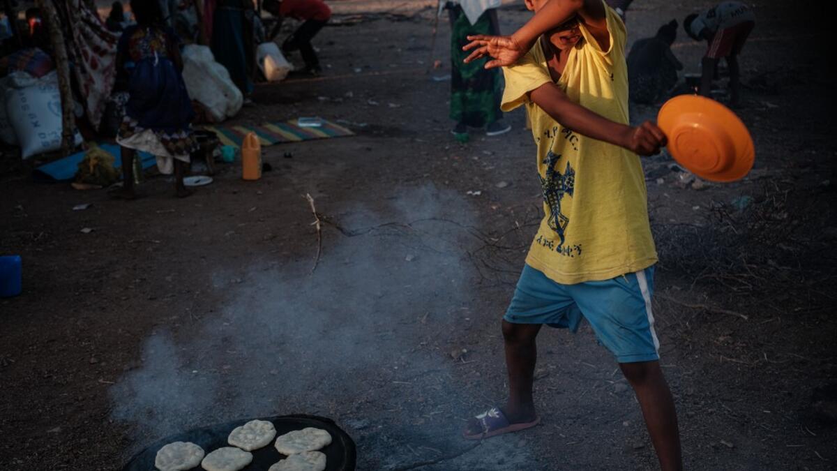 An Ethiopian boy, who fled the Ethiopia's Tigray conflict as a refugee, avoids smoke as he helps to cook at Um Raquba refugee camp in Gedaref, eastern Sudan, on December 1, 2020. Yasuyoshi CHIBA / AFP