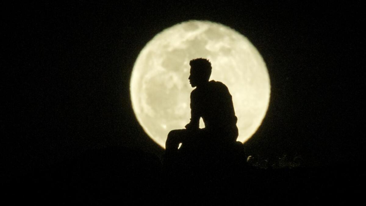 An Ehiopian man, who fled the Ethiopia's Tigray conflict as a refugee, watches the rising Moon on top of a hill at Um Raquba refugee camp in Gedaref, eastern Sudan, on December 1, 2020. Yasuyoshi CHIBA / AFP