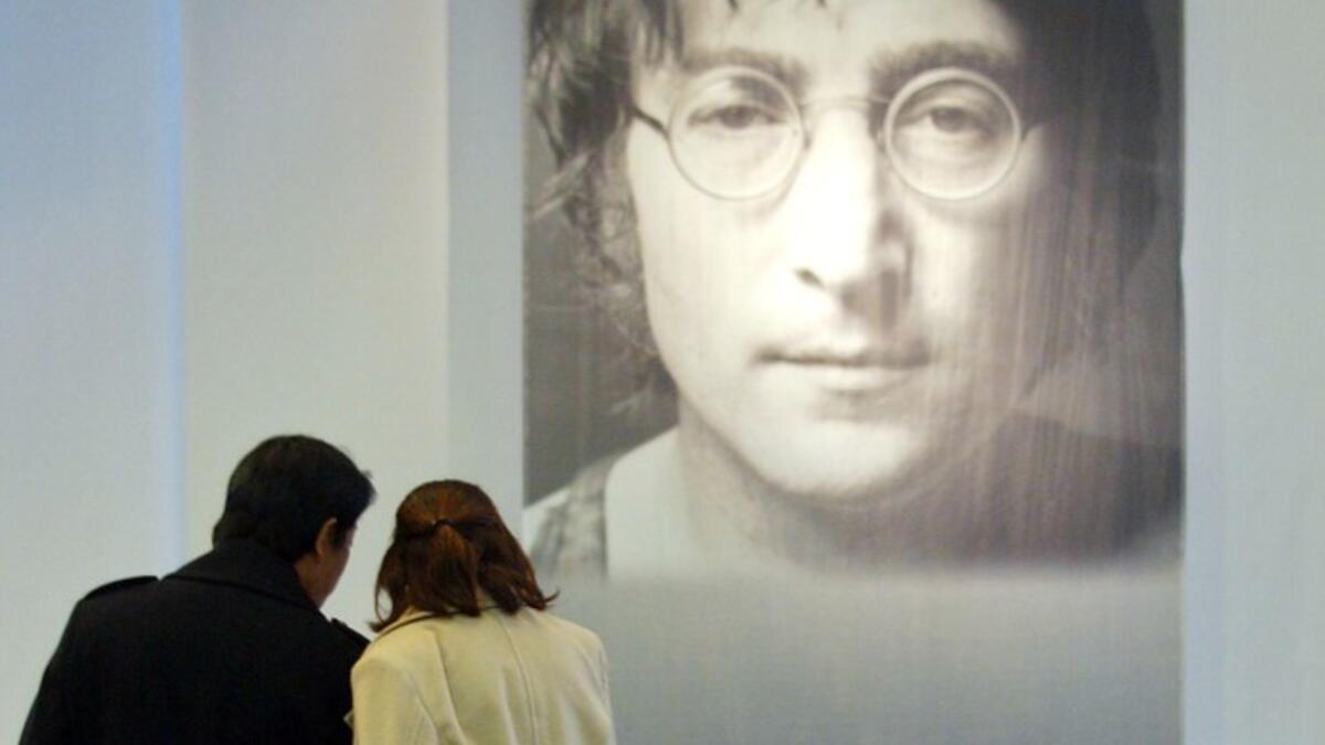 In this file photo taken on December 09, 2002 a Japanese couple place bouquets in front of a big portrait of former Beatle John Lennon at the John Lennon Museum before a charity concert to commemorate the 22nd anniversary of his death in Saitama, suburban Tokyo, 09 December 2002. John Lennon's career was cut short 40 years ago, on December 8, 1980, when he was shot dead in New York. AFP