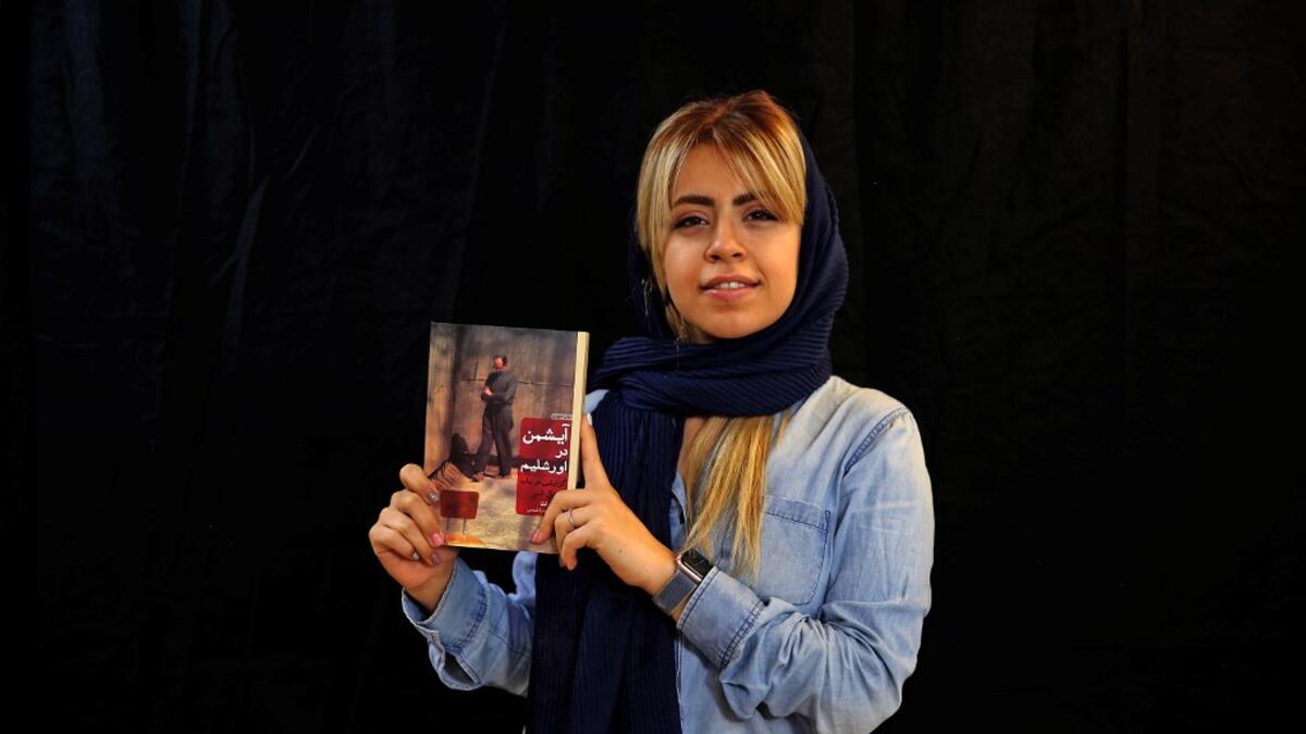 Employee Peghah Jafarieh poses with a bestselling book of the Saless Publishing House in Iran's capital Tehran, on October 11, 2020. ATTA KENARE / AFP