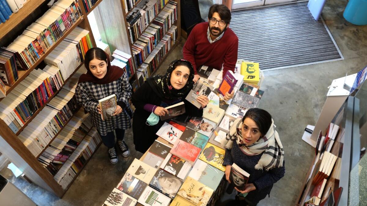 Employees pose for a picture at a bookstore of the Nashre-Cheshmeh Publishing House on Karim Khan street in the Iranian capital Tehran, on December 5, 2020. ATTA KENARE / AFP