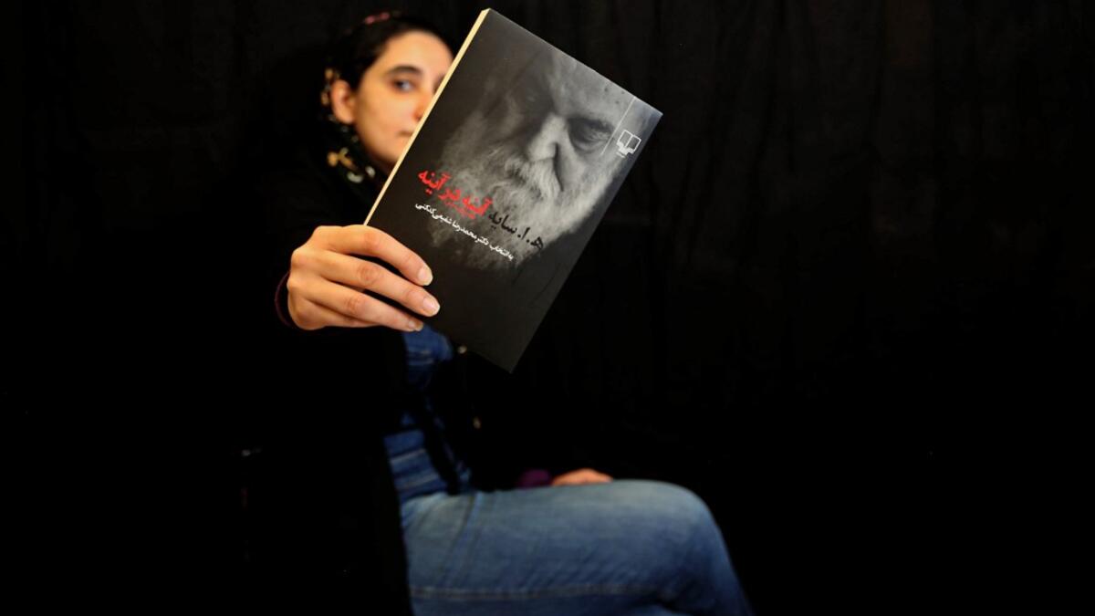 Employee Mahnaz Zabi poses with a bestselling book of the Nashre-Cheshmeh Publishing House in Iran's capital Tehran, on December 5, 2020. ATTA KENARE / AFP