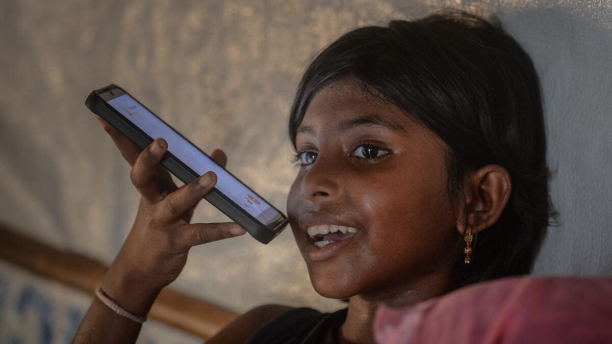 In this photograph taken on October 8, 2020, the daughter of Rohingya refugee Arofa Khatun, who tried to migrate with her two daughters to Malaysia to her husband, speaks on the phone with her father at a makeshift shelter in Kutupalong refugee camp in Ukhia. Stay in a squalid refugee camp -- hopeless, starving, and made to feel a burden -- or leave, risking death, rape, human trafficking and months at sea to reach a husband you've never met. This is the bleak choice many Rohingya women, already scarred fro
