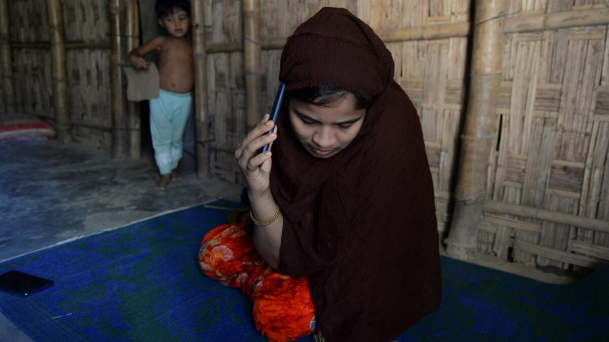 In this photograph taken on October 13, 2020, Rohingya refugee Umme Khair, who gave money to a community leader to travel to Malaysia to her husband, speaks on her mobile phone at a makeshift shelter in Kutupalong Rohingya refugee in Ukhia. Stay in a squalid refugee camp -- hopeless, starving, and made to feel a burden -- or leave, risking death, rape, human trafficking and months at sea to reach a husband you've never met. This is the bleak choice many Rohingya women, already scarred from fleeing persecuti