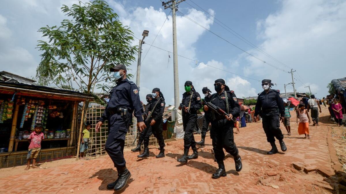 In this photograph taken on October 7, 2020, Rapid Action Battalion (RAB) personnel patrol along a street in Jamtoli refugee camp for Rohingyas in Ukhia. Boatloads of Rohingya landing across Southeast Asia are victims of complex human trafficking networks run by a dizzying web of players, from crime bosses and corrupt cops to poor fishermen, rickshaw drivers and even Rohingya themselves. Munir UZ ZAMAN / AFP