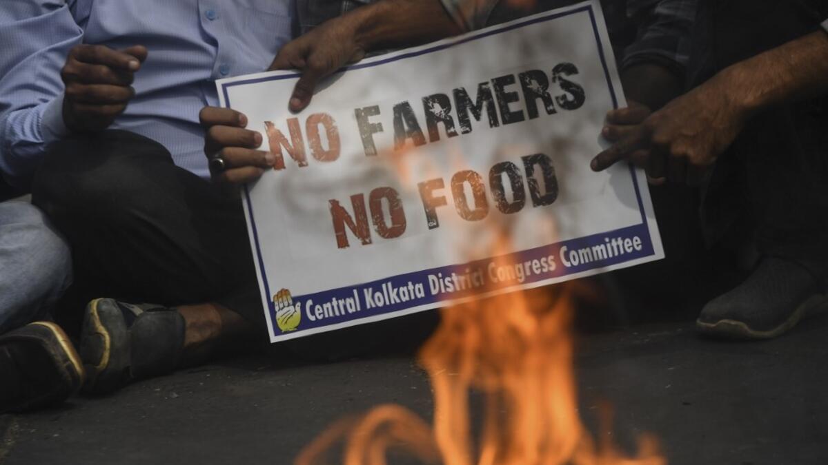 Congress activists hold placards next to a burning an effigy of Prime Minister Narendra Modi while blocking a road during a protest in support of the nationwide general strike called by farmers against the recent agricultural reforms in Kolkata on December 8, 2020. Dibyangshu SARKAR / AFP