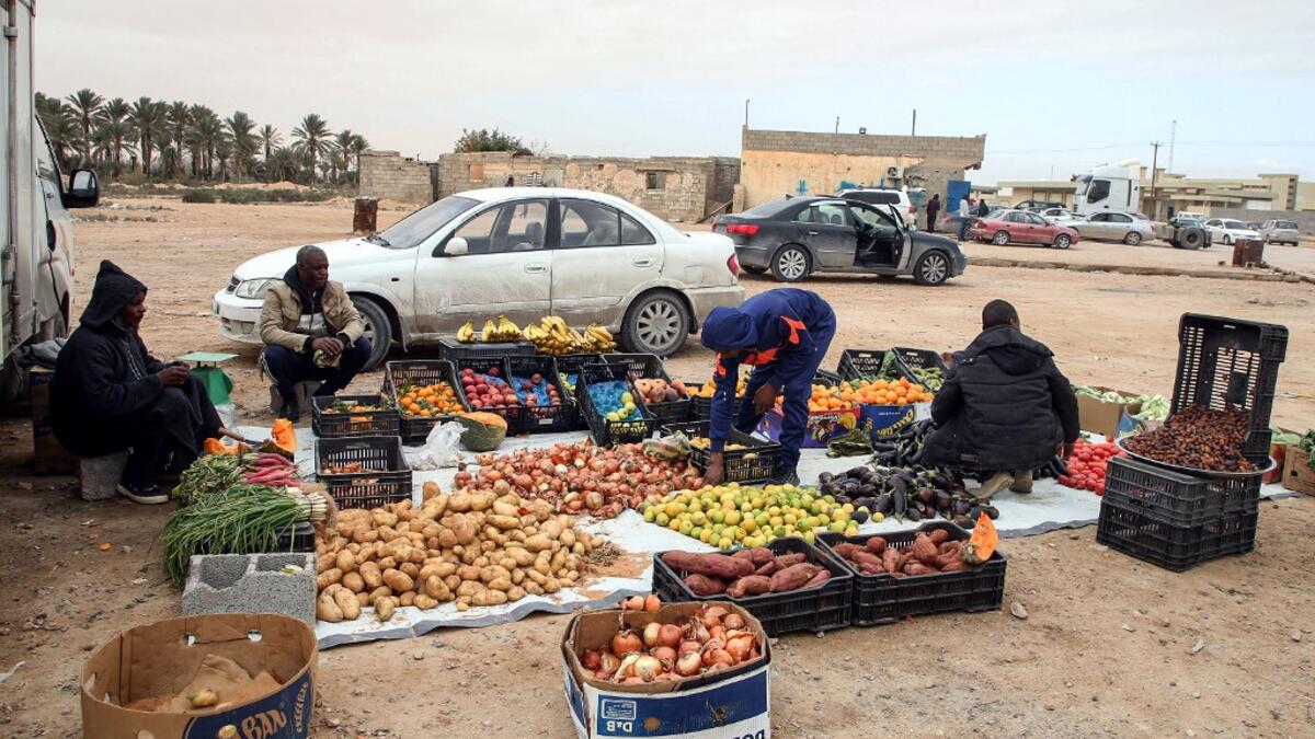 Produce vendors sit by their fruit and vegetable merchandise in the open in the city of Tawergha, some 200 kilometres (125 miles) east of Libya's capital close to the port city of Misrata, on December 12, 2020. When Libyan dictator Moamer Kadhafi was toppled, people took revenge on those they saw as his supporters -- including the entire town of Tawergha, whose 40,000 residents were forced to flee. Now, almost a decade later since militia forces rampaged through the town torching homes, destroying buildings
