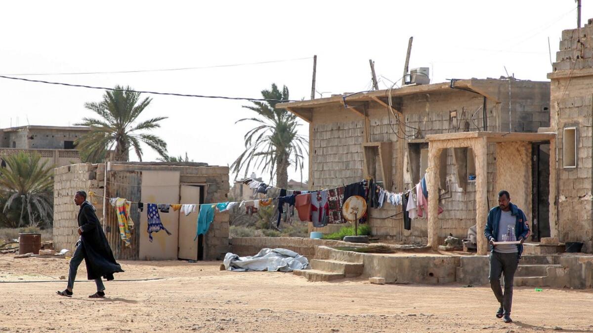 A man walks near a laundry clothing line hanging in the open by a building in the city of Tawergha, some 200 kilometres (125 miles) east of Libya's capital close to the port city of Misrata, on December 12, 2020. When Libyan dictator Moamer Kadhafi was toppled, people took revenge on those they saw as his supporters -- including the entire town of Tawergha, whose 40,000 residents were forced to flee. Now, almost a decade later since militia forces rampaged through the town torching homes, destroying buildin