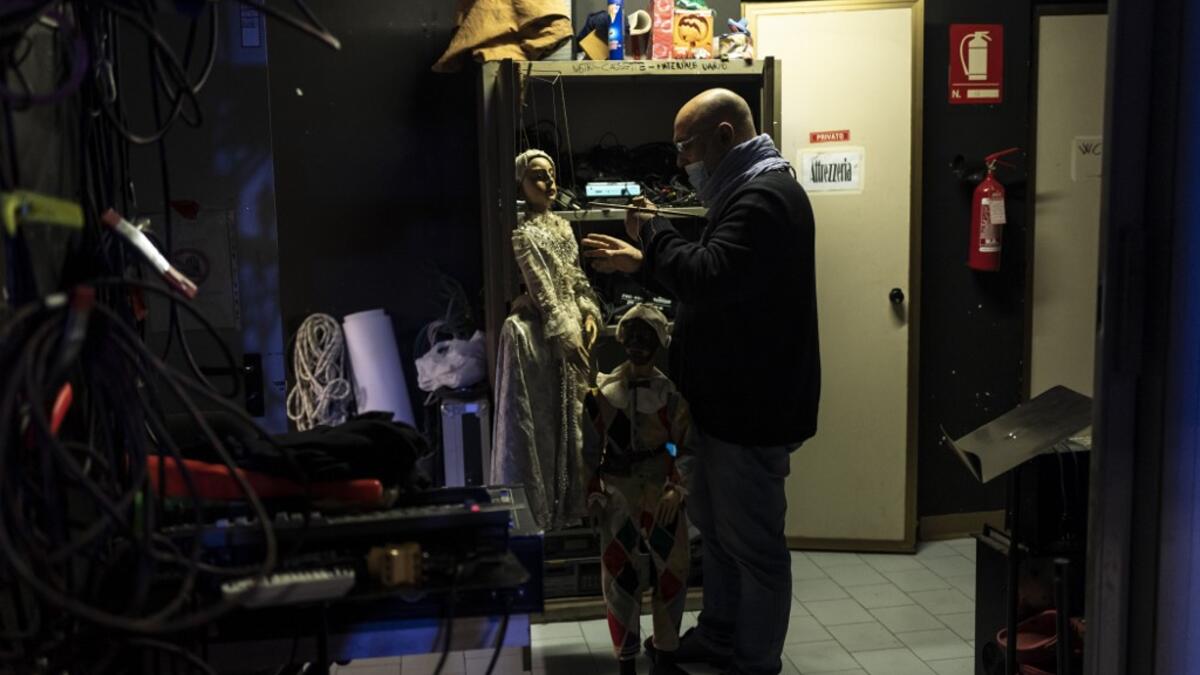 Marco Grilli holds two puppets backstage at the " Alfa Theatre" in Turin, on November 30, 2020. The Grilli family has a collection of more than 20,000 objects from around the world, everything from theatres, marionettes and glove puppets to shadow figures and silhouettes. A long-time dream of Grilli and his wife Mariarosa, 78, the museum is due to open in 2023 in Turin, financed both privately and publicly with the help of different institutions.  Marco Bertorello / AFP