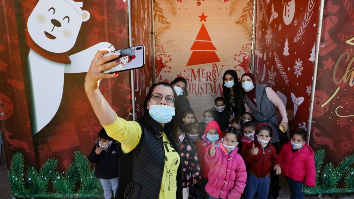 A Palestinian school teacher takes a 'selfie' photograph with her pupils, ahead of Christmas in the biblical city of Bethlehem in the occupied West Bank, amid the novel coronavirus pandemic crisis, on December 19, 2020. Christmas mass in Bethlehem, normally attended by Christian congregations in the West Bank town, will be closed to the public this year due to Covid-19 restrictions, the Palestinian president said earlier this week. The Palestinian Authorities imposed a new lockdown in several governorates i