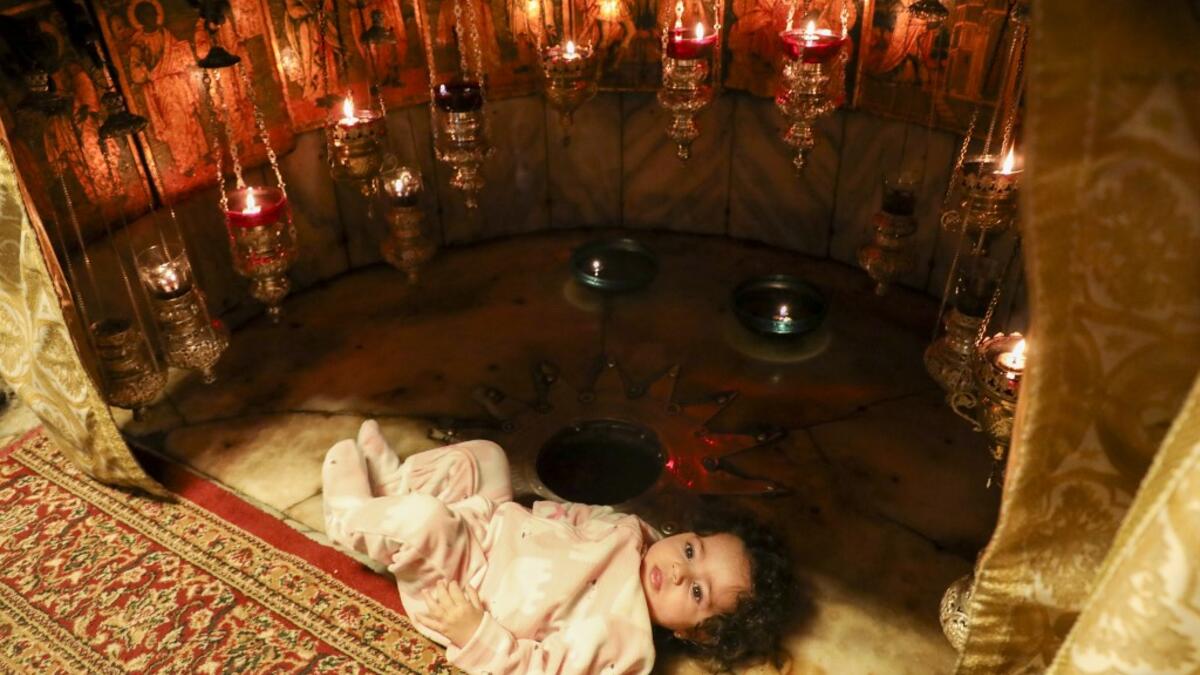 A child is pictured near the 14-pointed silver star at the Grotto, believed to be the exact spot where Jesus Christ was born and where Christian worshippers come to pray in the Church of the Nativity, in the West Bank city of Bethlehem, on December 20, 2020. The church was re-opened for prayers following strict COVID-19 restrictions imposed by the Palestinian authorities to curb the spread of the novel coronavirus. HAZEM BADER / AFP