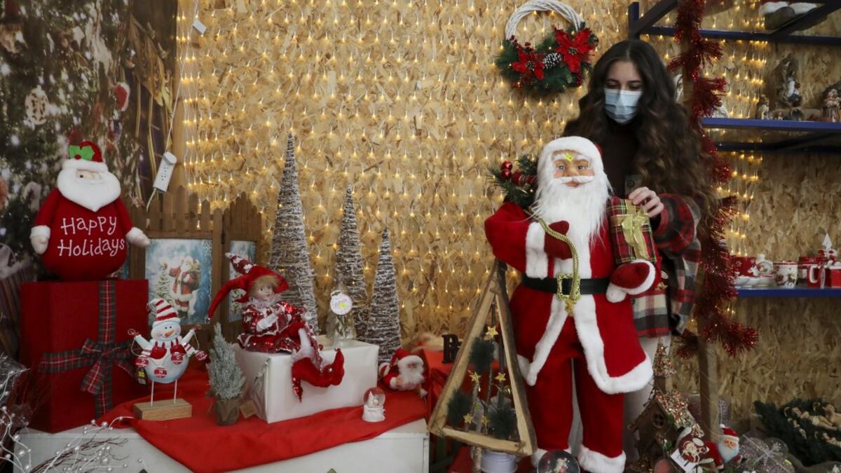 A Palestinian shop-owner arranges Christmas decorations at her shop in the West Bank city of Bethlehem on December 21, 2020. HAZEM BADER / AFP