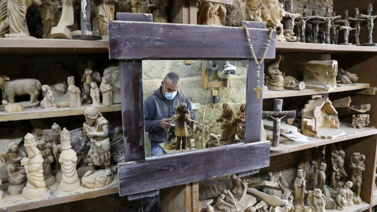 A Palestinian carpenter carves religious statues and figurines from olive wood at a shop near the Church of the Nativity, in the West Bank city of Bethlehem on December 21, 2020. HAZEM BADER / AFP
