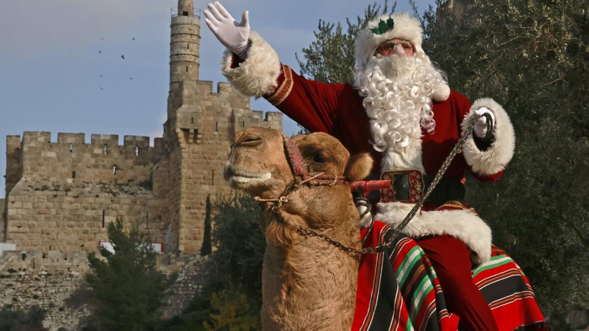 Issa Kassissieh, better known as the Santa Claus of Jerusalem, rides a camel on December 22, 2020 outside Jerusalem's Old City walls. MENAHEM KAHANA / AFP