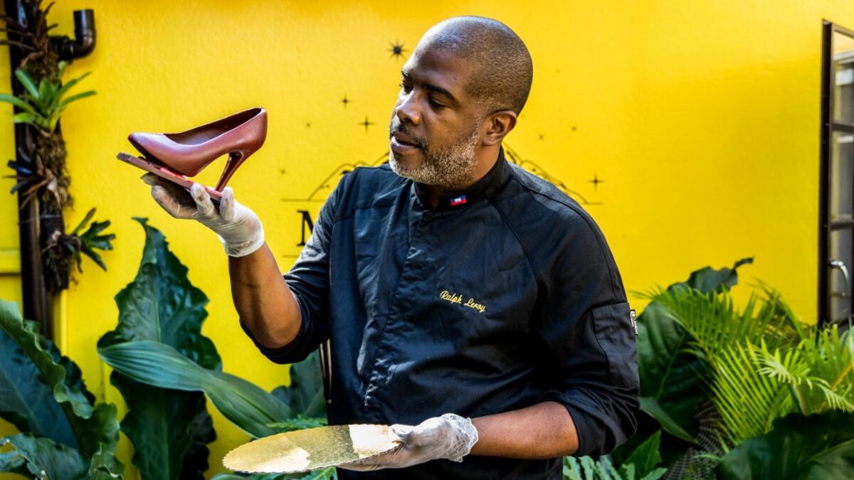 Ralph Leroy, chocolate maker, entrepreneur and chocolate sculptor, poses with one of his emblematic creations, a shoe in the workshops of Makaya Chocolat on December 23, 2020 in Petionville, Haiti. Although small in the face of South America's giants, Haiti is slowly developing its cocoa industry to ensure better incomes for thousands of modest farmers and to end the stereotype of gastronomic art known as the domain of wealthy countries. Valerie Baeriswyl / AFP