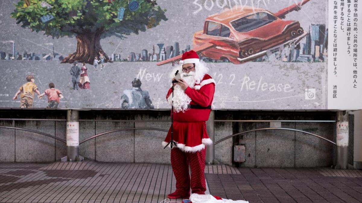 A lone performer dressed as Santa Claus prepares for his performance on Christmas eve, in Shibuya district of Tokyo on December 24, 2020. Philip FONG / AFP