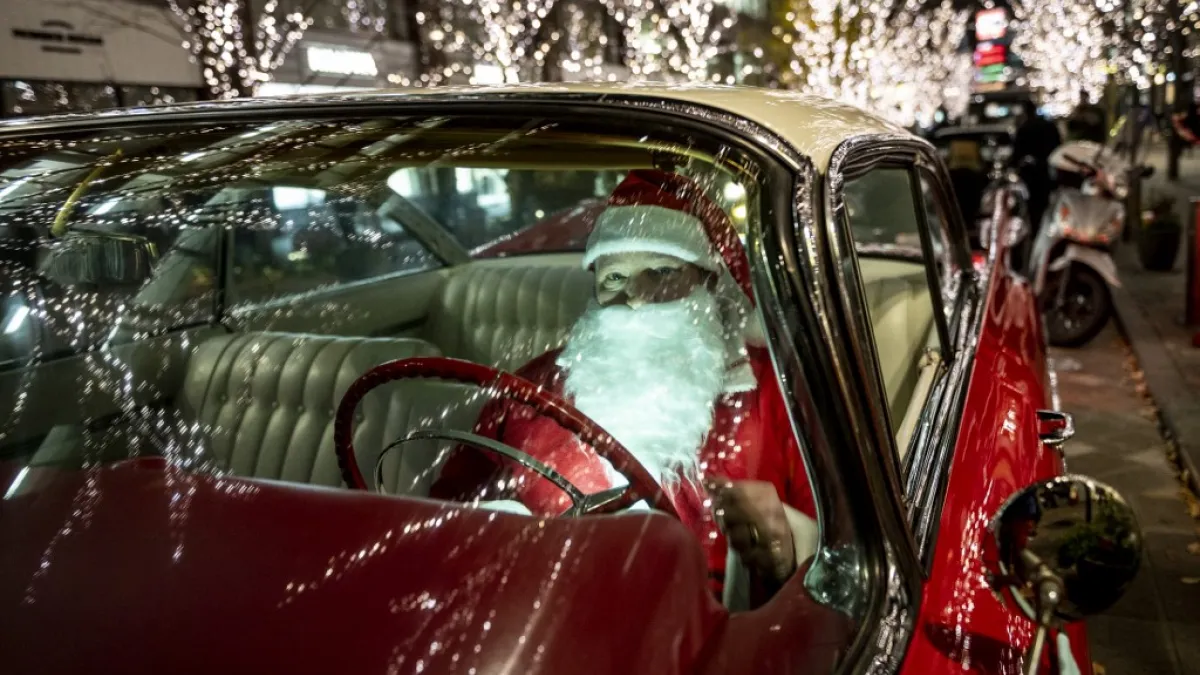 Rob Holtzapfel, a member of a vintage car group dressed as Santa Claus, sits in a 1959 Cadillac along a street lined with Christmas-themed light decorations in Marunouchi district in Tokyo on December 25, 2020. Philip FONG / AFP
