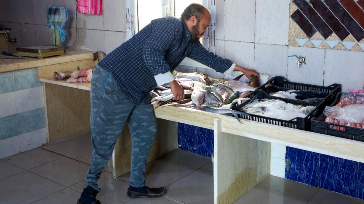 Libyan fishmonger Radwan Jibril who uses a prosthetic leg after an injury amid clashes in 2011, works at his shop in the port city of Misrata, on December 17, 2020. With Libya's health sector left in tatters by its multiple conflicts since the 2011 revolution, war-wounded Libyans are often sent abroad for treatment, at the expense of the state. However, A national centre for prostheses, being established in Misrata, already has a patient waiting list of more than 3,000 amputees