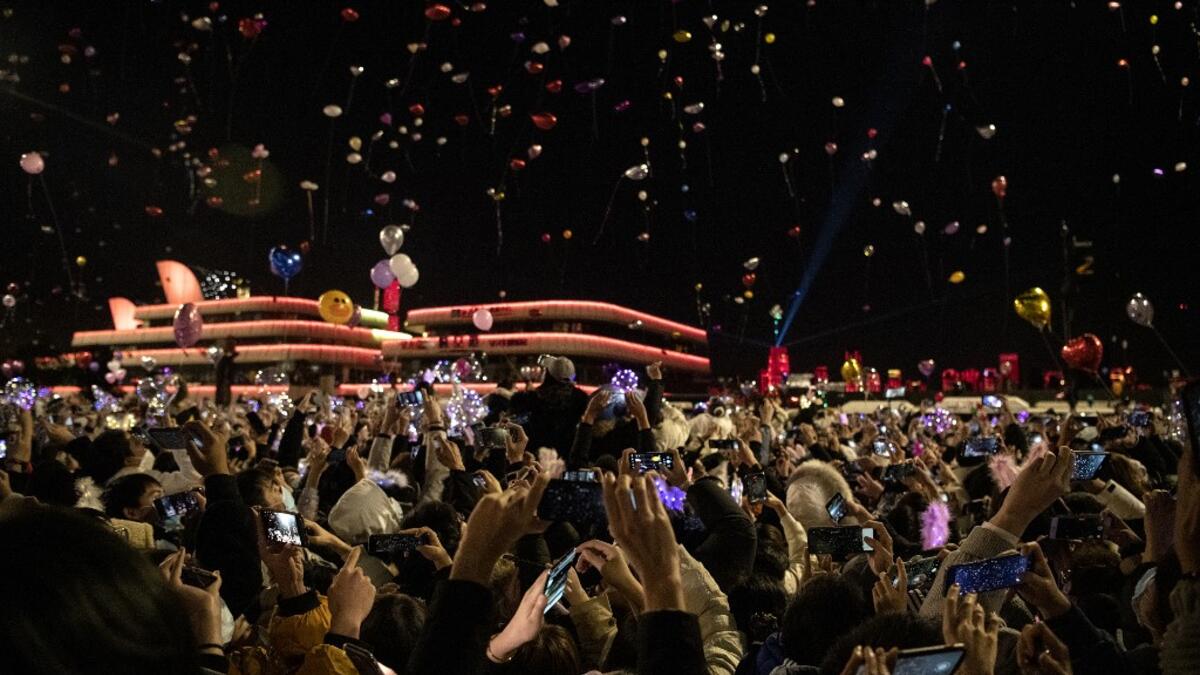 People wearing face masks release balloons during a New Year's countdown in Wuhan in China’s central Hubei province on January 1, 2021. NOEL CELIS / AFP