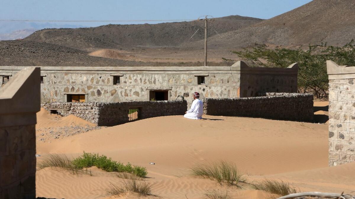 Mohammed al-Ghanbousi, a former inhabitant of Wadi al-Murr, kneels to pray on a sand dune among abandoned houses in the Omani village, about 400 kms (250 miles) southwest of the capital Muscat, on December 31, 2020. MOHAMMED MAHJOUB / AFP