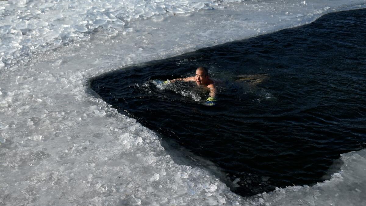 An ice swimmer swims in a frozen lake on a cold winter day in Beijing on January 6, 2021. WANG Zhao / AFP