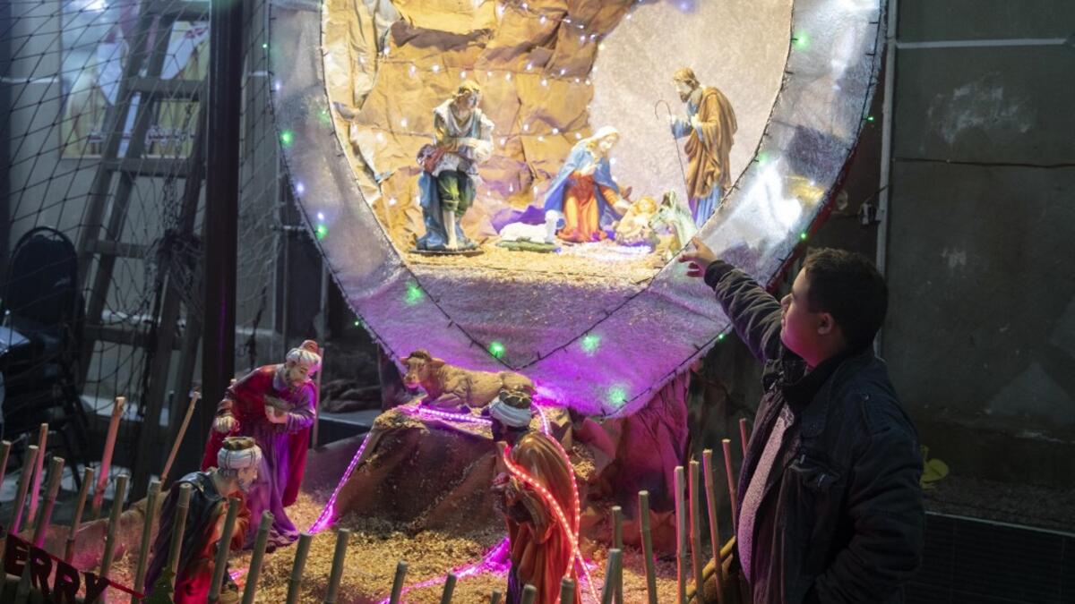 An Egyptian Christians worshipper stands by a nativity scene as he attends the Christmas Eve mass at the Coptic Catholic St. Mark Church in Minya city, some 245 kilometres south of the capital Cairo on January 6, 2021.   Roger ANIS / AFP