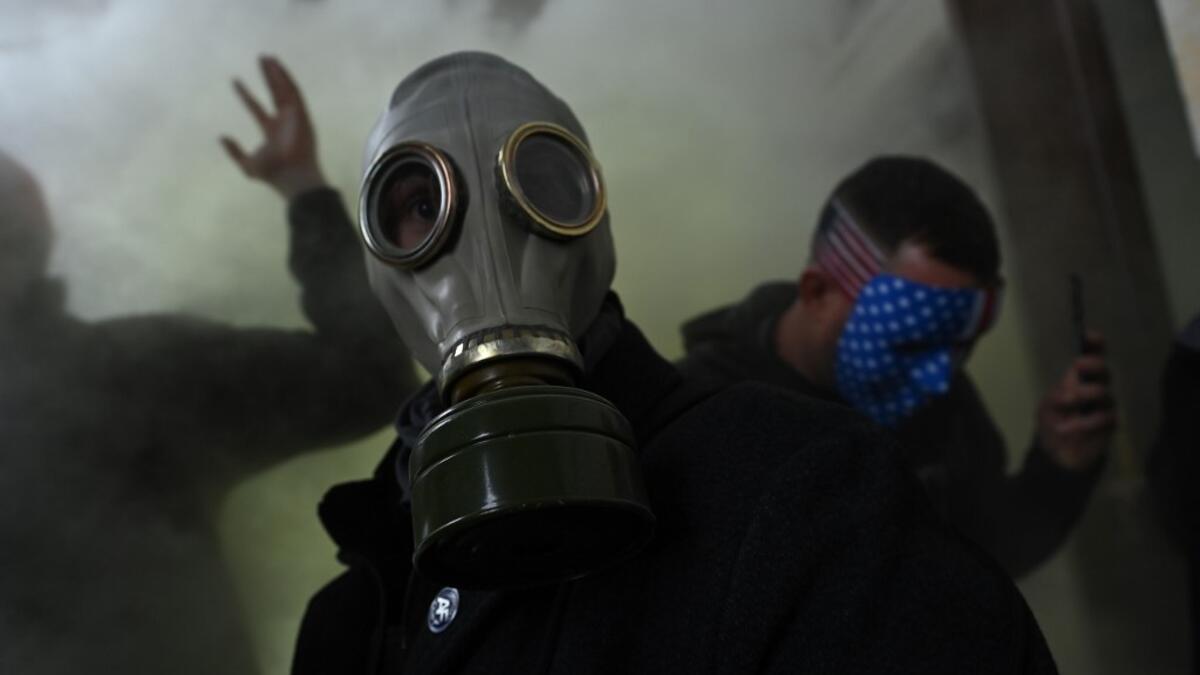 A supporter of US President Donald Trump wears a gas mask as he protests after storming the US Capitol on January 6, 2021, in Washington, DC. Demonstrators breeched security and entered the Capitol as Congress debated the a 2020 presidential election Electoral Vote Certification. President-elect Joe Biden denounced the storming of the US Capitol as an "insurrection" and demanded President Donald Trump go on television to call an end to the violent "siege." Brendan SMIALOWSKI / AFP