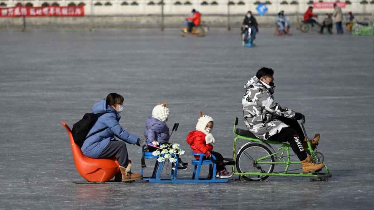 A family uses a sled on a frozen lake in Beijing on January 12, 2021. WANG Zhao / AFP