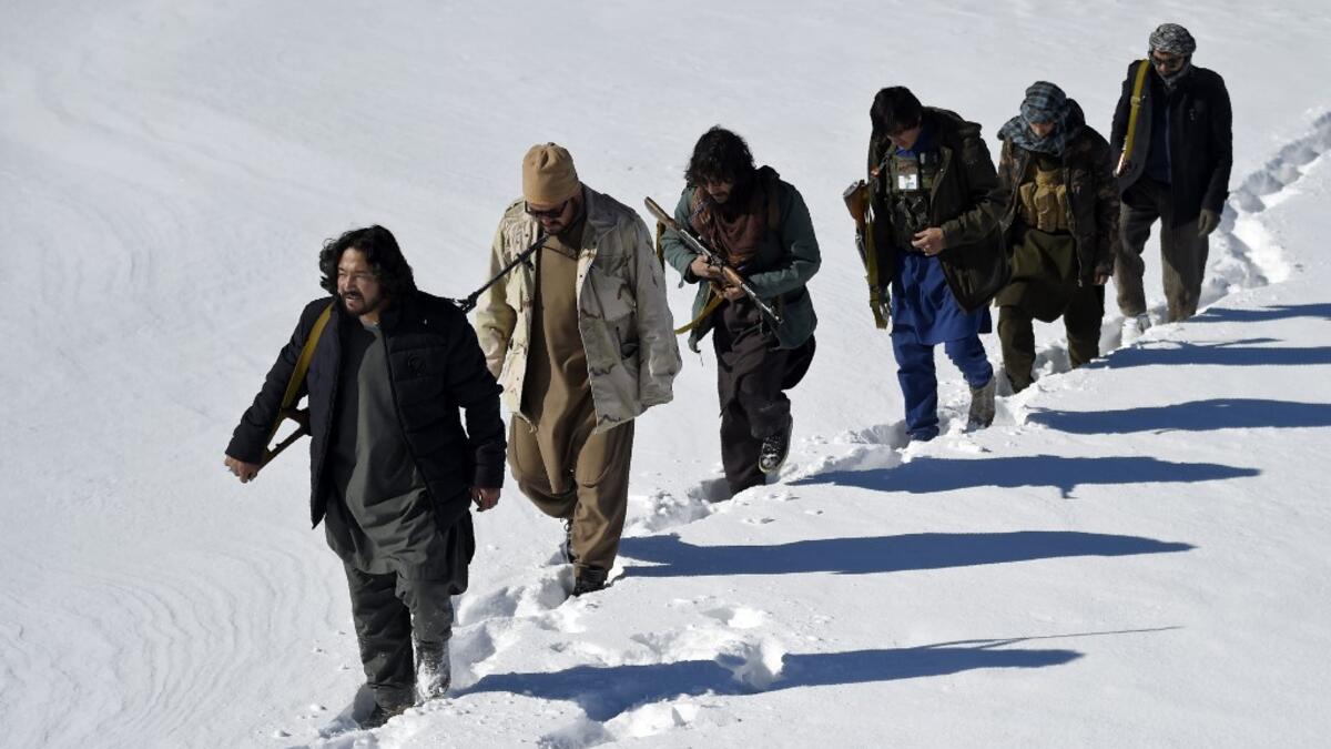 In this photo taken on January 9, 2021, Hazara armed militia for the Resistance for Justice Movement, walk on a snow-covered path during a patrol against Taliban insurgents at Hisa-e-Awali Behsud district of Maidan Wardak Province. Comprising roughly 10 to 20 percent of Afghanistan's 38-million population, Hazaras have long been persecuted for their largely Shiite faith by Sunni hardliners in a country wracked by deep ethnic divisions. WAKIL KOHSAR / AFP