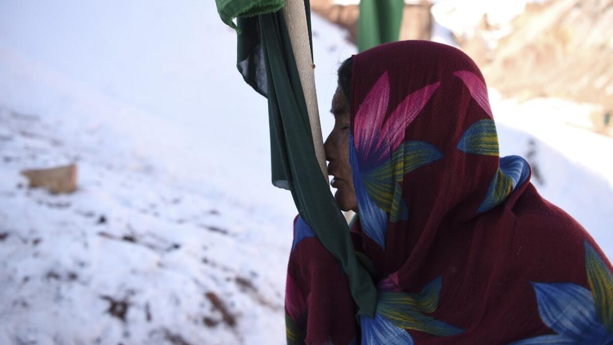 In this photo taken on January 6, 2021, a Hazara woman Jawahir Sedaqat, who lost two sons in an explosions on November 24 last year in the city of Bamiyan, prays and kisses a flag at a graveyard of her sons in Somarah village on the outskirts of Bamiyan province. Comprising roughly 10 to 20 percent of Afghanistan's 38-million population, Hazaras have long been persecuted for their largely Shiite faith by Sunni hardliners in a country wracked by deep ethnic divisions. WAKIL KOHSAR / AFP