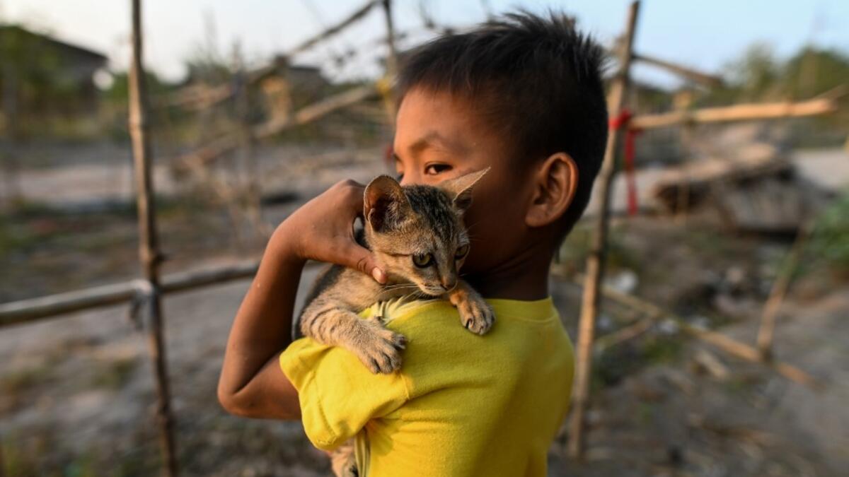 This photo taken on January 11, 2021 shows a Chin child playing with his cat in Bethel village in Hmawbi, on the outskirts of Yangon, where hundreds of members of the Chin ethnic community have settled after being displaced by fighting between Myanmar's military and the Arakan Army in the country's north.  Ye Aung THU / AFP
