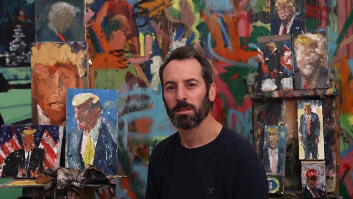 Israeli painter Iddo Markus poses for a picture at his studio, surrounded by his paintings of former US president Donald Trump, in the northern port city of Haifa, on January 22, 2021. Markus became fascinated by the "tragic figure" of Donald Trump, and the walls and floor of his studio are packed with some 120 portraits of the former US presidents. Emmanuel DUNAND / AFP