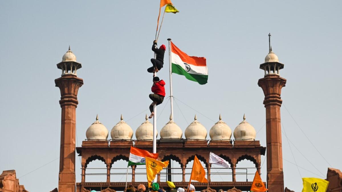 Protesters climb a flagpole at the ramparts of the Red Fort as farmers continue to demonstrate against the central government's recent agricultural reforms in New Delhi on January 26, 2021. Sajjad HUSSAIN / AFP