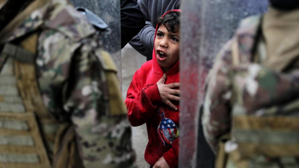 A boy gestures as Lebanese anti-government protesters confront security forces while going around the homes of deputies and government officials in the northern port city of Tripoli to protest the economic situation and their role in leading the country to crisis, on January 28, 2021. Tripoli was already one of Lebanon's poorest areas before the coronavirus pandemic piled new misery onto a chronic economic crisis. Many of its residents have been left without an income since Lebanon imposed a full lockdown e