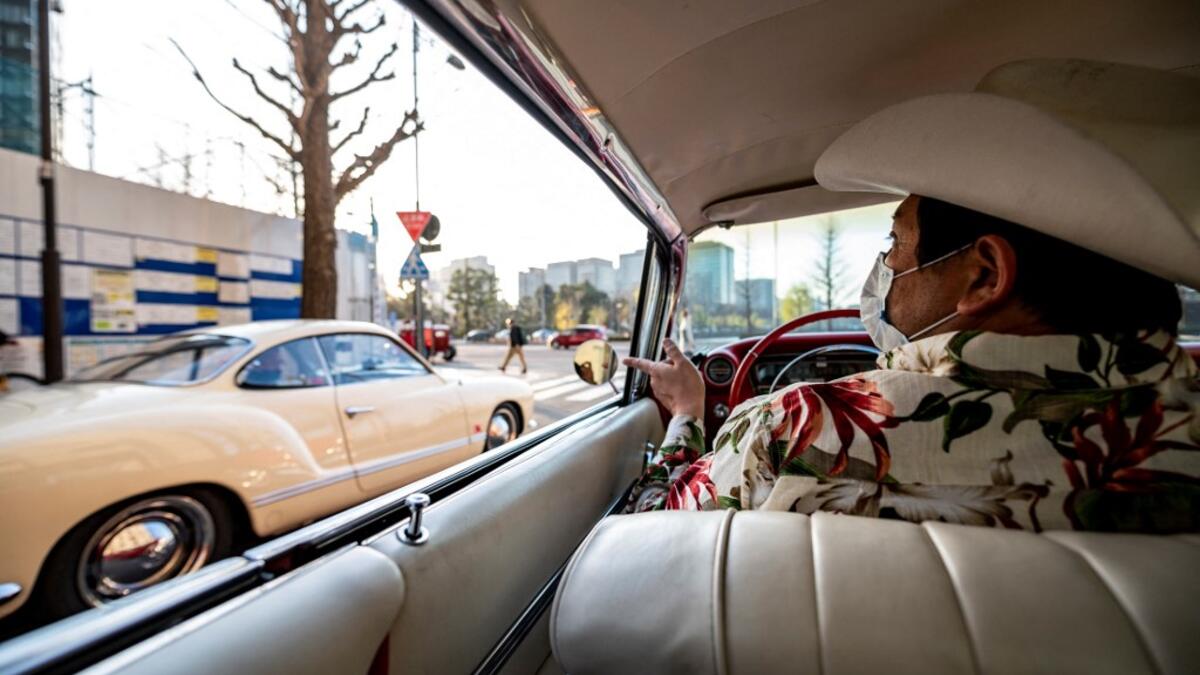This picture taken on January 16, 2021 shows Hiroyuki Wada, who runs a vintage car service company, driving a 1959 Cadillac Coupe DeVille during a gathering of auto enthusiasts in Tokyo. A loose club of fans rolls up most weekends in central Tokyo to show off their Cadillacs, Chevrolets and other modern classic vehicles from the mid to late 20th century. Philip FONG / AFP