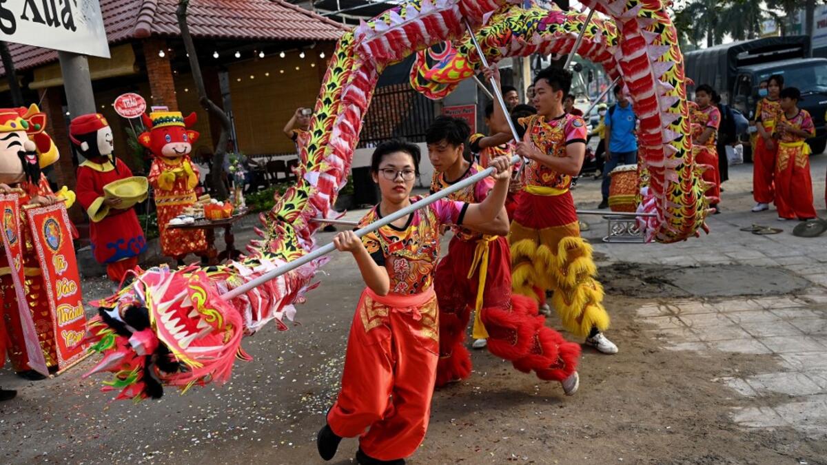 This photograph taken on January 21, 2021 shows Le Yen Quyen (C) of the Tu Anh Duong lion and dragon dance school performing a dragon dance outside a newly-opened cafe in Can Tho city in southern Vietnam's Mekong Delta. Manan VATSYAYANA / AFP